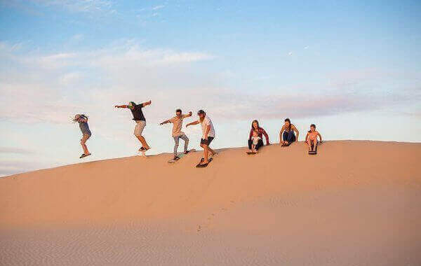 Sand surfing riding down a dune in Timlalin.