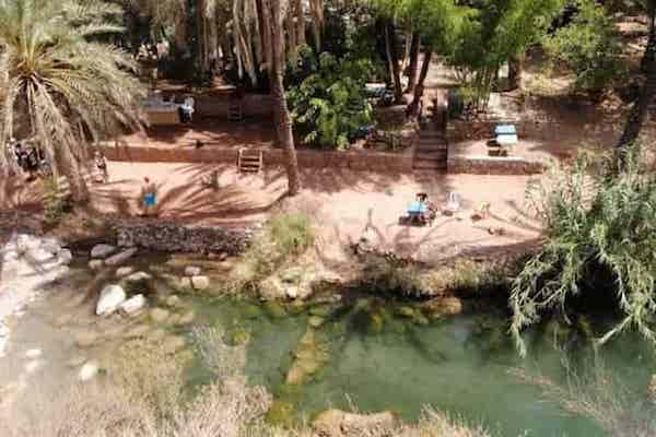 A traveler mid-air while cliff jumping into the turquoise waters of Paradise Valley during a Paradise Valley day trip from Taghazout.